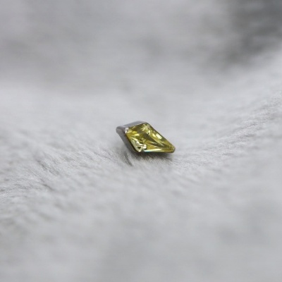 Pedra preciosa amarela em forma de losango sobre tecido cinza aveludado