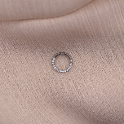 anel pequeno de metal com pedras sobre tecido bege