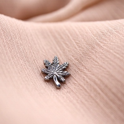 Botão metálico em forma de folha sobre tecido rosa claro