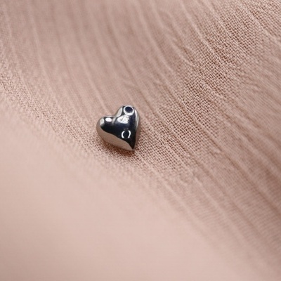 Brinco coração prateado sobre tecido rosa claro