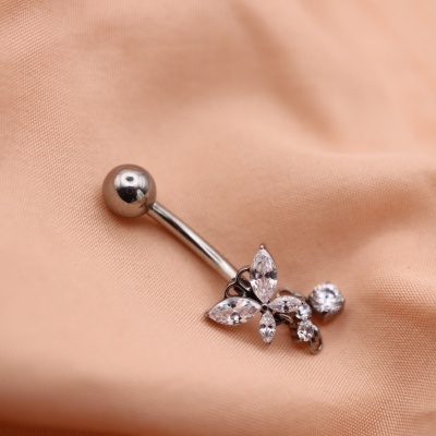 Piercing de umbigo em metal prateado com pedras transparentes sobre tecido salmão