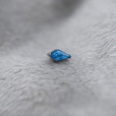 Pedra preciosa azul losango sobre tecido cinzento felpudo