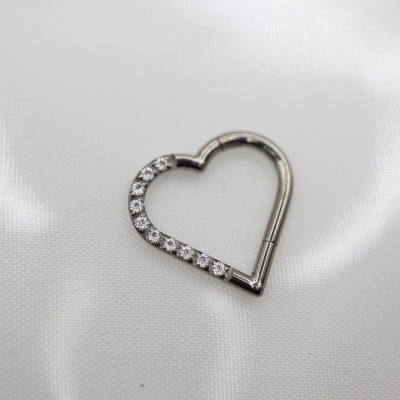 Fecho coração prateado com pedras sobre tecido branco
