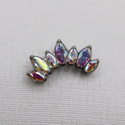 Brinco curvo com pedras iridescentes sobre tecido bege