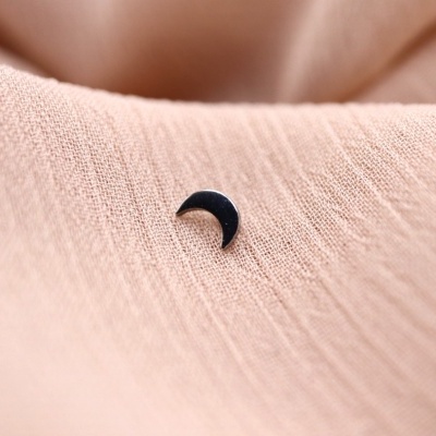 Brinco lua pequena preto sobre tecido rosa claro