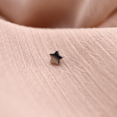 Pequena estrela preta sobre tecido rosa claro com textura