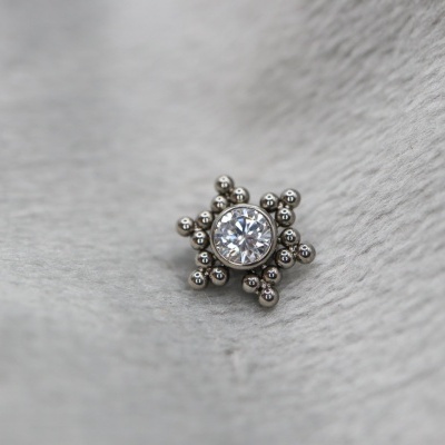 Brinco metálico prateado com pedra central redonda e padrão de estrela