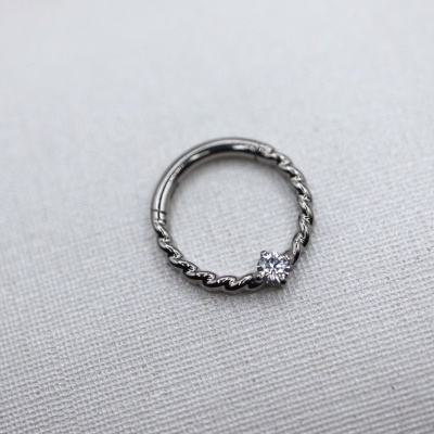 Argola prateada com pedra brilhante sobre tecido branco