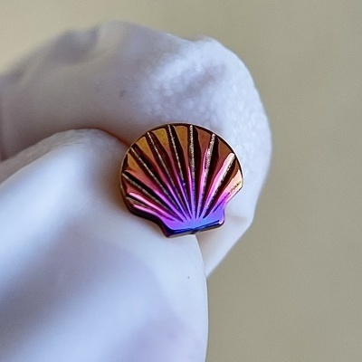 Brinco em forma de concha em metal iridescente com luva branca