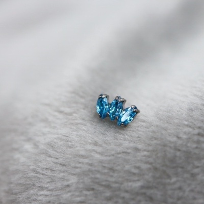 Brinco pequeno com três pedras azuis em fundo branco macio