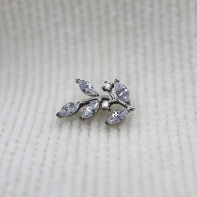 Brinco prateado com pedras em forma de ramo sobre tecido branco