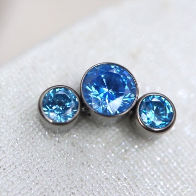 Três botões com pedras azuis sobre tecido branco