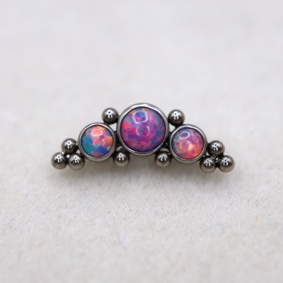 Broche metálico com pedras coloridas sobre superfície clara