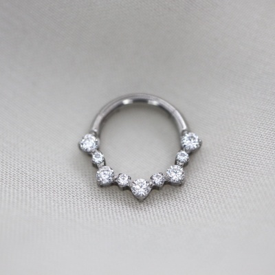 Argola prateada com pedras sobre tecido cinzento