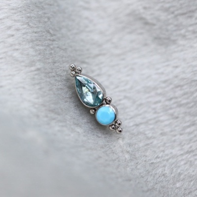 pendente em prata com pedras azuis sobre fundo cinzento