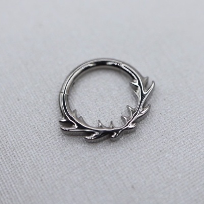 Argola de metal prateado com design de galhos em tecido branco