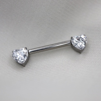 Piercing de barra com pedras em formato de coração sobre tecido cinza claro