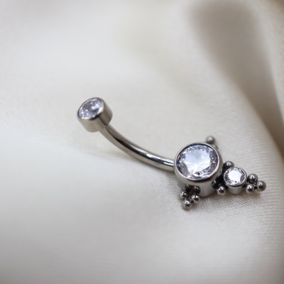 Brinco prateado para umbigo com pedras transparentes sobre tecido branco