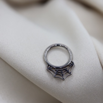 Anel de prata com design de teia de aranha sobre tecido bege