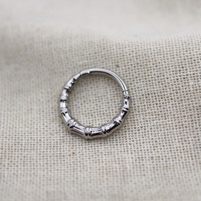 Argola de metal prateado sobre tecido bege claro