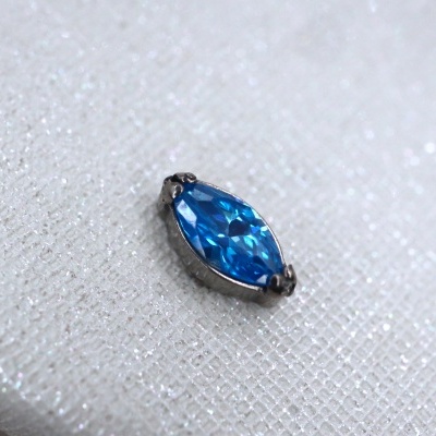 Peça de bijuteria com pedra azul oval em fundo branco