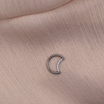 Argola pequena em formato de lua com pedras sobre tecido bege claro