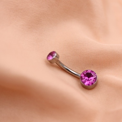 Piercing com pedras roxas em tecido cor de pêssego