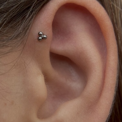 Piercing prateado de três esferas na parte superior da orelha