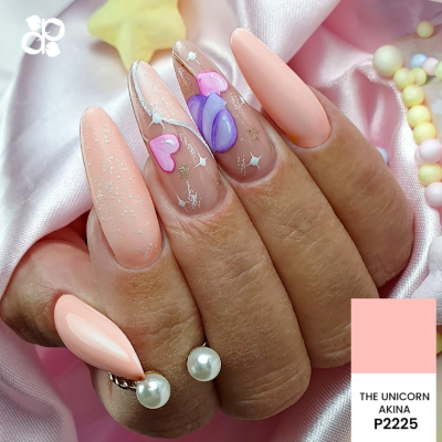 Unhas decoradas com verniz rosa salmão, corações rosa e estrelas prateadas sobre tecido rosa