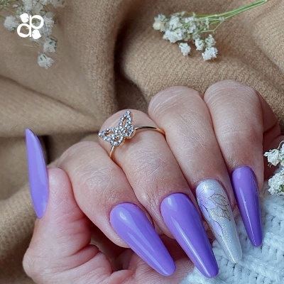 Unhas longas roxas e prata com anel borboleta e flores brancas secas