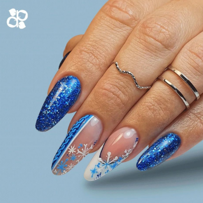 Unhas decoradas com azul brilhante e padrões de flocos de neve, mãos com anéis prateados