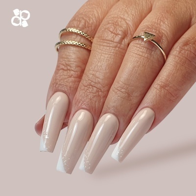 Mão com unhas francesinha bege e branco com três anéis dourados