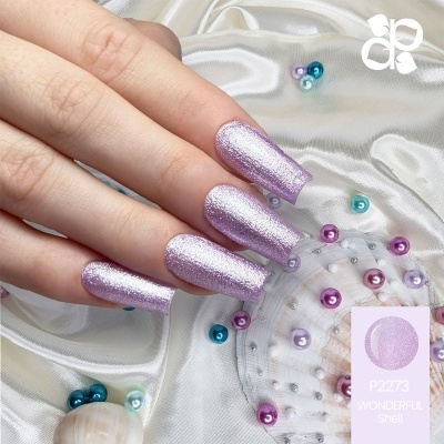 Unhas com verniz roxo cintilante em fundo de tecido branco com pérolas e concha decorativa