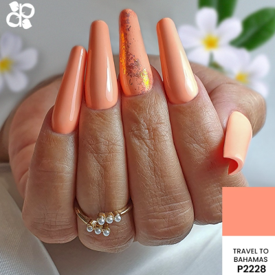 Unhas compridas estilo coffin com verniz laranja pêssego e padrão marmoreado num dedo, com anéis e flores ao fundo