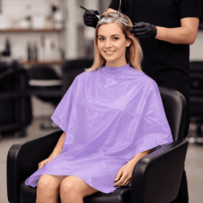 Mulher com capa de plástico lavanda num salão de beleza