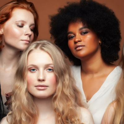 Cinco mulheres com diferentes tons de pele e cabelos diversos numa pose juntas