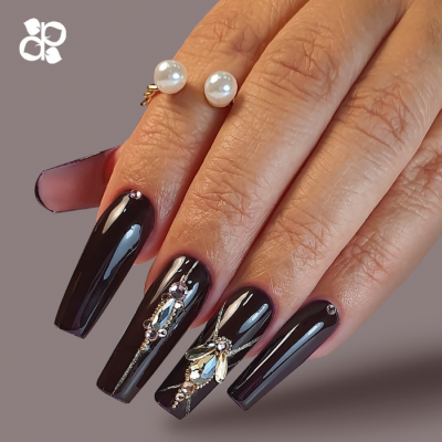 Mãos femininas com unhas postiças pretas decoradas e anel de pérolas