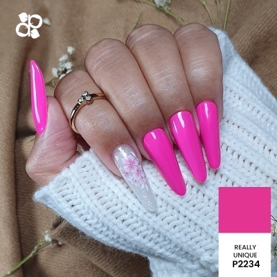 Mão com unhas stiletto rosa vibrante e unha decorada com flor rosa, manga de malha branca