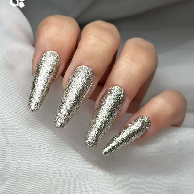 Unhas prateadas glitteradas compridas sobre tecido branco