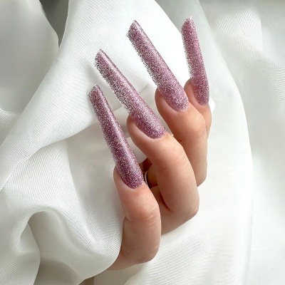 Unhas postizas cor-de-rosa brilhantes em mão sobre tecido branco