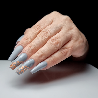 Mão feminina com unhas cinza claro e detalhes dourados