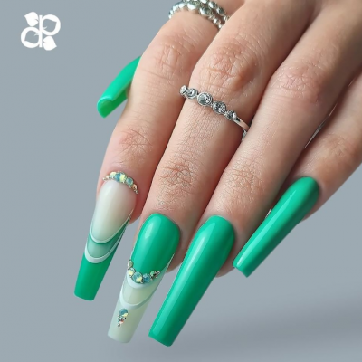 Mão feminina com unhas verdes e decoração com pedras, usando anéis prateados