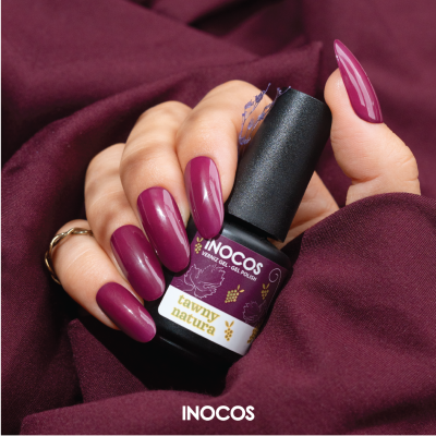 Mão com unhas bordeaux segurando tinta de verniz gel INOCOS tawny natura