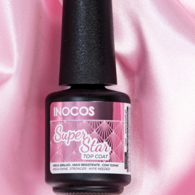 Frasco de verniz INOCOS Super Star Top Coat sobre tecido rosa