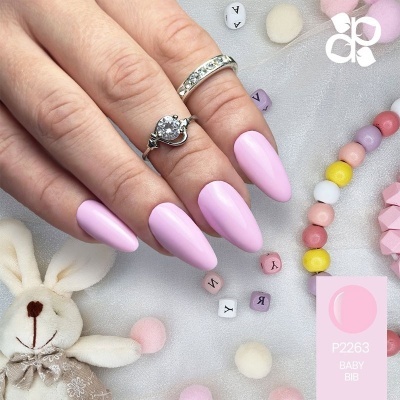 Unhas artificiais rosa claro com anéis prateados e esferas coloridas num fundo cinza com coelho de pelúcia