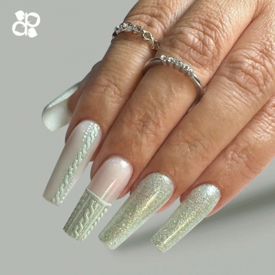 Mão com unhas decoradas em branco e glitter com anéis prateados.