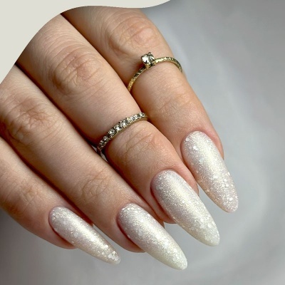 Mão com unhas compridas brancas peroladas e anéis delicados