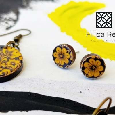 Conjunto de brincos em madeira com padrão floral amarelo e preto e logótipo Filipa Reis