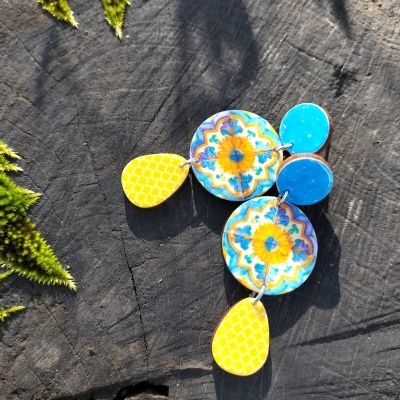 Brincos coloridos em madeira sobre madeira escura com musgo