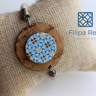 Pulseira de madeira com pendente decorativo colorido sobre almofada têxtil
